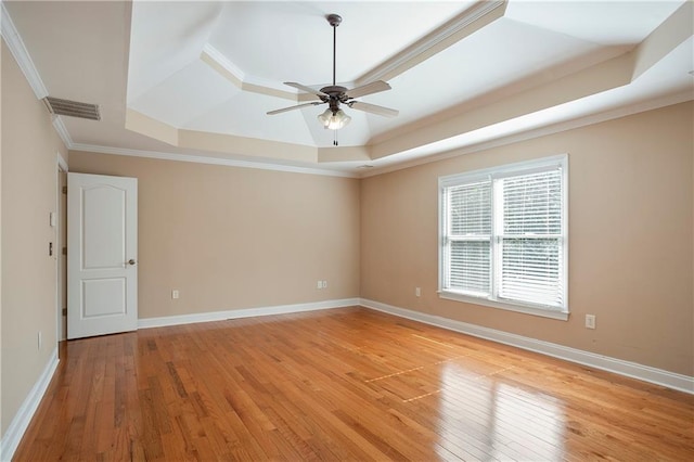 spare room featuring ornamental molding, ceiling fan, a tray ceiling, and light hardwood / wood-style flooring