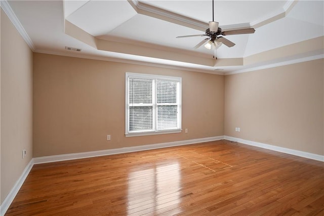 spare room featuring a raised ceiling, crown molding, and light hardwood / wood-style floors