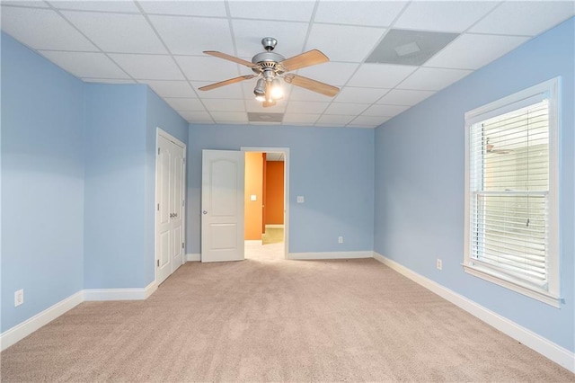 spare room with a paneled ceiling, light colored carpet, and ceiling fan