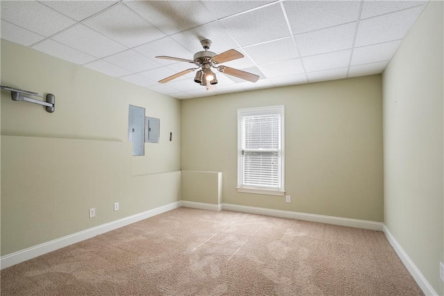 empty room featuring light carpet, electric panel, a paneled ceiling, and ceiling fan