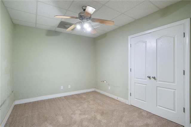 unfurnished bedroom with light carpet, a drop ceiling, and ceiling fan