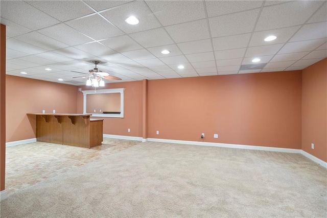 unfurnished living room with a drop ceiling, ceiling fan, indoor bar, and light colored carpet
