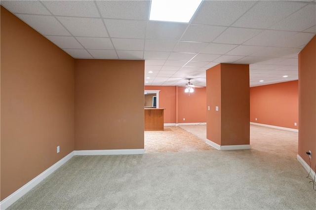basement featuring ceiling fan, a paneled ceiling, and light colored carpet