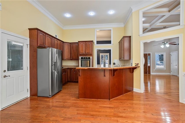 kitchen with a kitchen bar, hardwood / wood-style flooring, appliances with stainless steel finishes, and kitchen peninsula