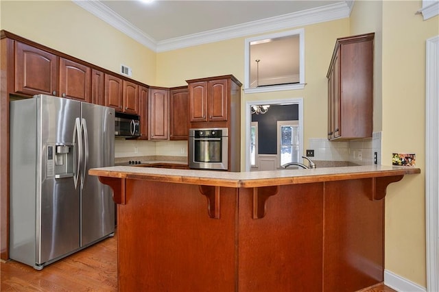 kitchen with ornamental molding, stainless steel appliances, light wood-type flooring, and kitchen peninsula
