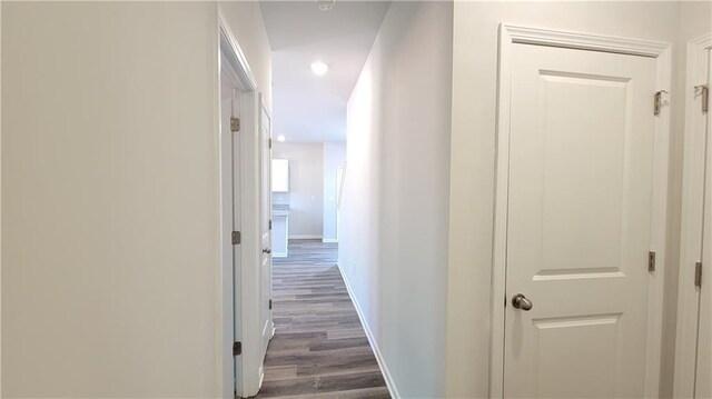 corridor with dark wood-style floors and baseboards