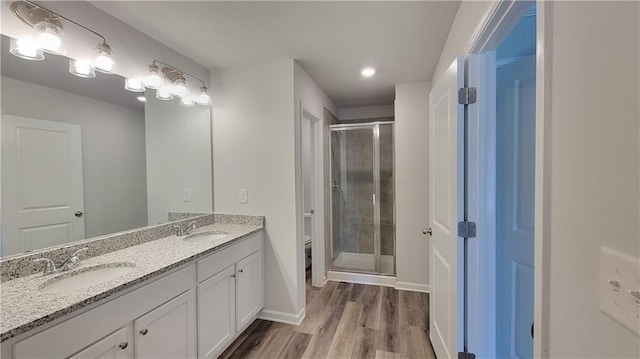 bathroom with wood finished floors, a sink, toilet, and a shower stall