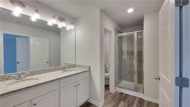 bathroom with a sink, a shower stall, toilet, and wood finished floors