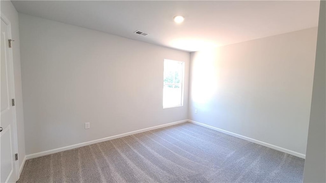 spare room with carpet floors, visible vents, and baseboards