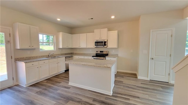 kitchen with stainless steel appliances, a sink, wood finished floors, visible vents, and white cabinets