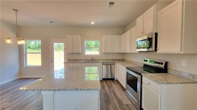 kitchen featuring visible vents, a center island, a sink, stainless steel appliances, and a wealth of natural light