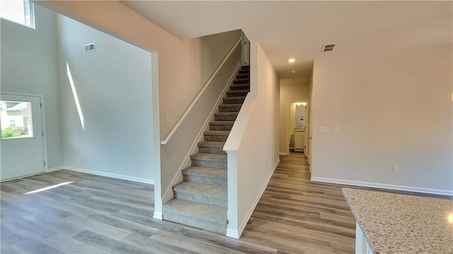 staircase with baseboards, visible vents, wood finished floors, and recessed lighting