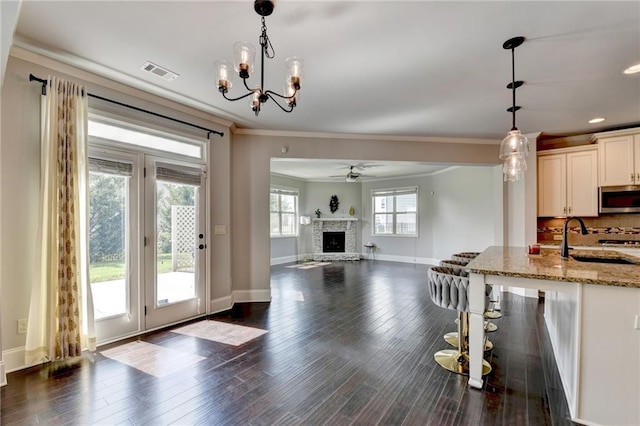 7470 Oldbury Pl, Cumming, GA 30040 - kitchen with stainless steel microwave, a sink, light stone countertops, a ceiling fan, and ornamental molding
