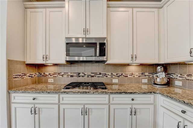 7470 Oldbury Pl, Cumming, GA 30040 - kitchen with appliances with stainless steel finishes, tasteful backsplash, white cabinetry, and light stone counters