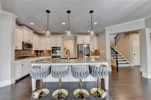 7470 Oldbury Pl, Cumming, GA 30040 - kitchen featuring stainless steel appliances, a sink, baseboards, crown molding, and a breakfast bar area