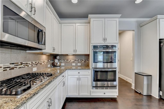 7470 Oldbury Pl, Cumming, GA 30040 - kitchen with stainless steel appliances, baseboards, tasteful backsplash, white cabinets, and crown molding