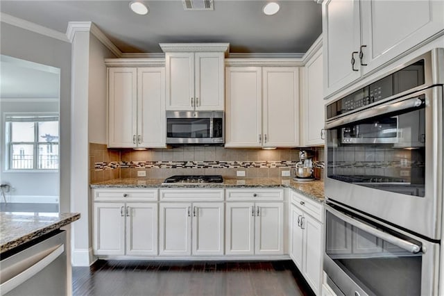 7470 Oldbury Pl, Cumming, GA 30040 - kitchen featuring stainless steel appliances, crown molding, white cabinets, light stone countertops, and tasteful backsplash