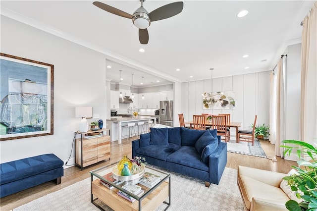 living room featuring crown molding, light hardwood / wood-style floors, sink, and ceiling fan