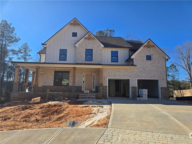 view of front facade with an attached garage, driveway, a porch, and board and batten siding