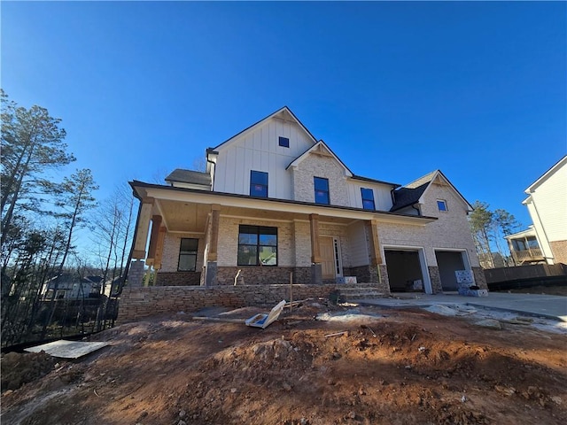 view of front facade featuring a garage, stone siding, a porch, and board and batten siding