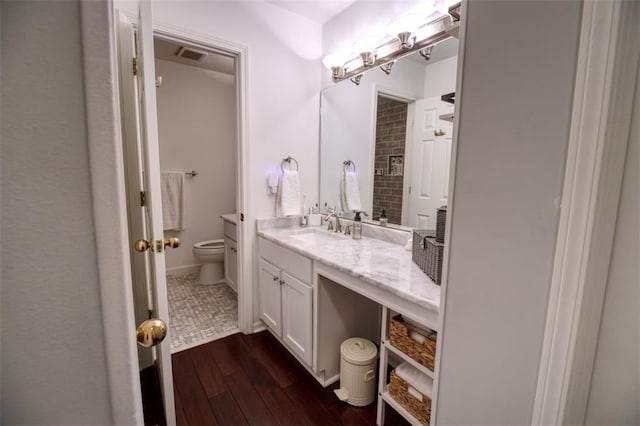 bathroom featuring wood-type flooring, vanity, and toilet