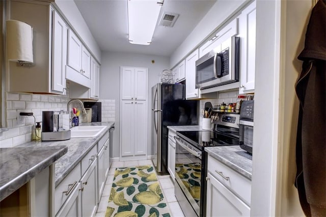 kitchen with light stone counters, sink, white cabinetry, and appliances with stainless steel finishes