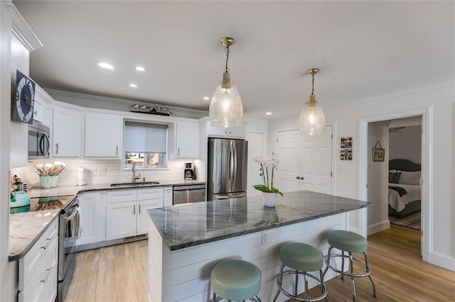 705 Berry Ct, Villa Rica, GA 30180 - kitchen with appliances with stainless steel finishes, a sink, white cabinets, ornamental molding, and a kitchen bar