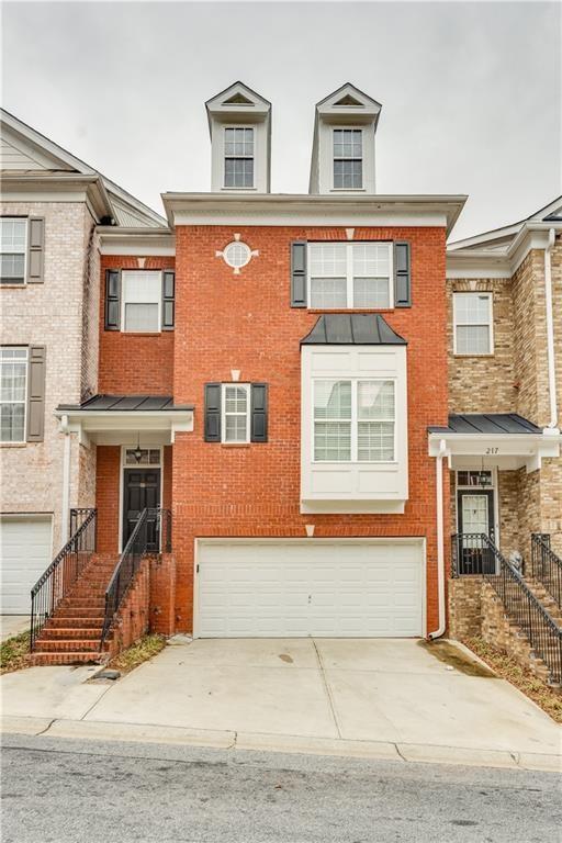 multi unit property featuring brick siding, concrete driveway, and an attached garage