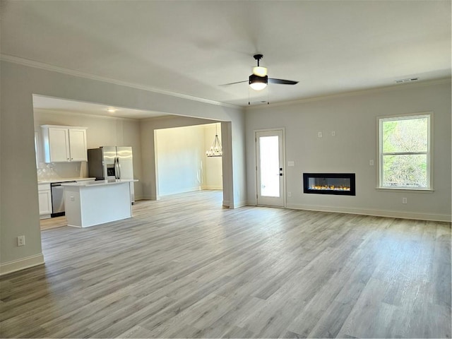 unfurnished living room featuring ceiling fan, crown molding, and light wood-type flooring