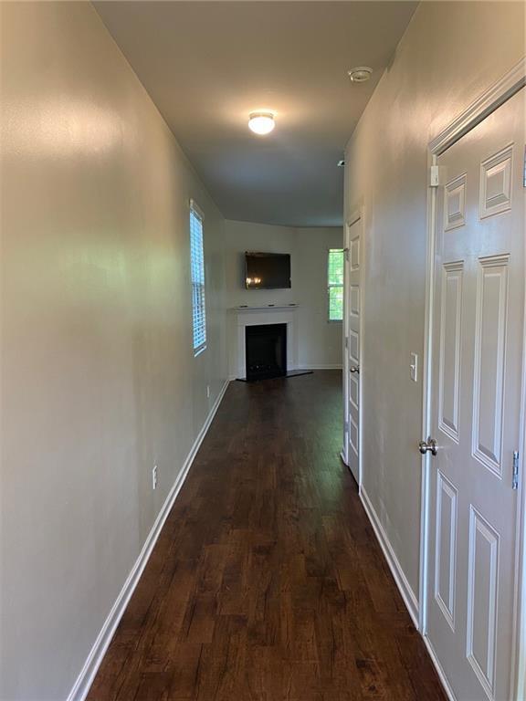 corridor featuring dark wood-style flooring and baseboards