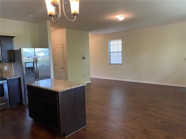 kitchen featuring stainless steel refrigerator with ice dispenser, dark wood finished floors, light stone countertops, a chandelier, and a center island