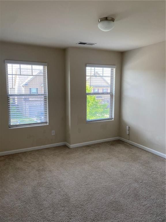 spare room featuring plenty of natural light, carpet, and baseboards