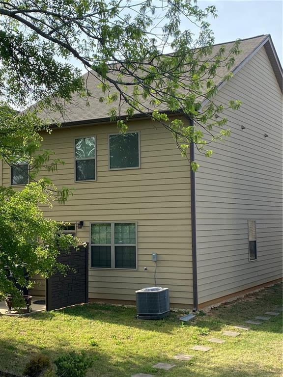 back of house with cooling unit and a lawn