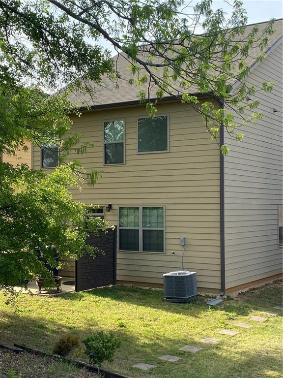 rear view of property featuring a lawn and central air condition unit