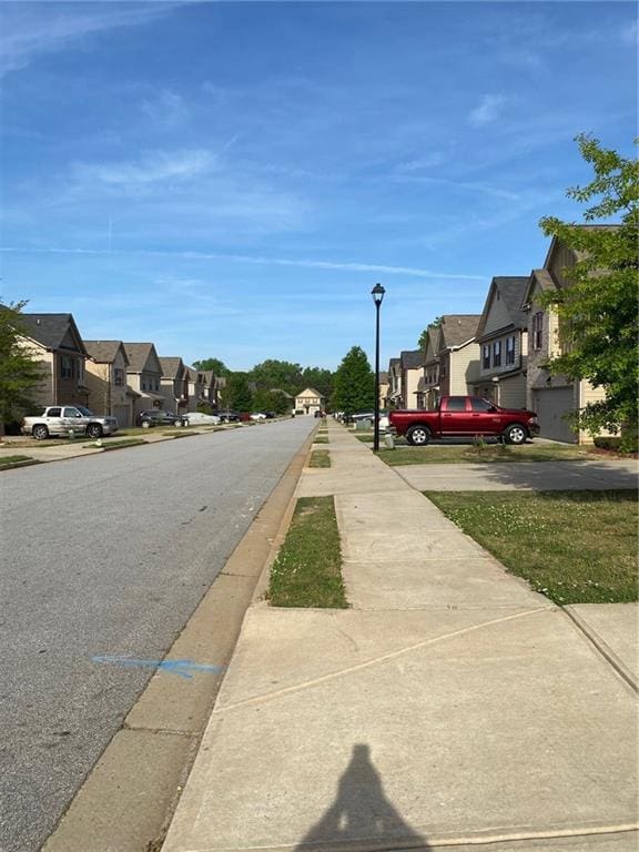 view of asphalt street with a residential view, sidewalks, and street lighting