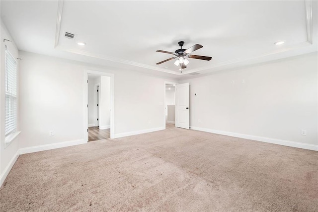 spare room featuring a raised ceiling, light colored carpet, a ceiling fan, baseboards, and recessed lighting