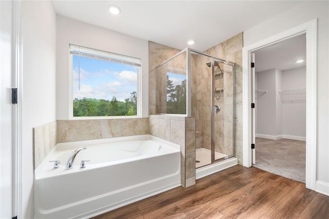 full bathroom with a shower stall, a garden tub, a walk in closet, wood finished floors, and recessed lighting