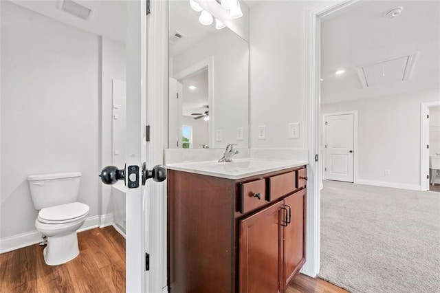 bathroom with toilet, vanity, baseboards, and wood finished floors