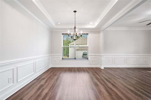 unfurnished dining area with a chandelier, dark wood-style flooring, a tray ceiling, a decorative wall, and a wainscoted wall