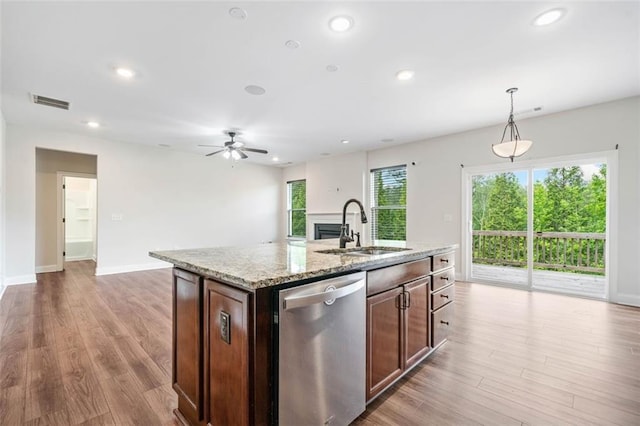 kitchen featuring dishwasher, a sink, light stone countertops, recessed lighting, and hanging light fixtures