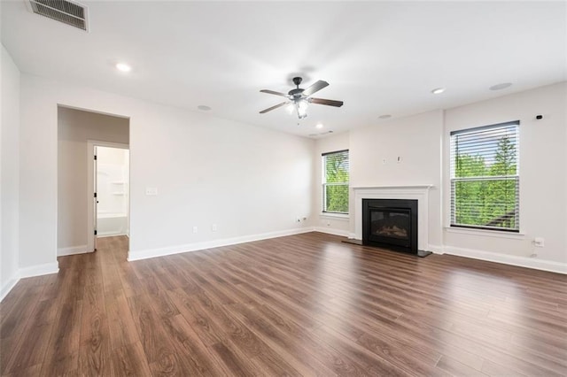 unfurnished living room featuring dark wood-type flooring, a glass covered fireplace, ceiling fan, baseboards, and recessed lighting
