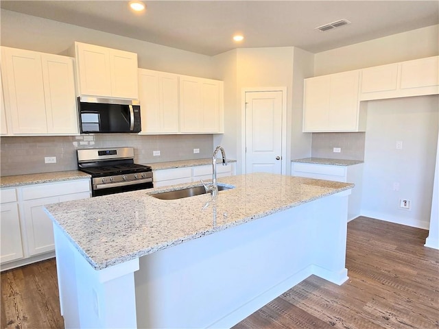 kitchen featuring stainless steel appliances, decorative backsplash, a sink, an island with sink, and wood finished floors