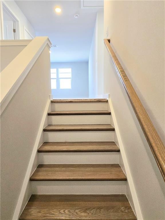 stairs with wood finished floors and recessed lighting