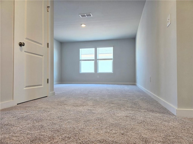 carpeted spare room with visible vents and baseboards