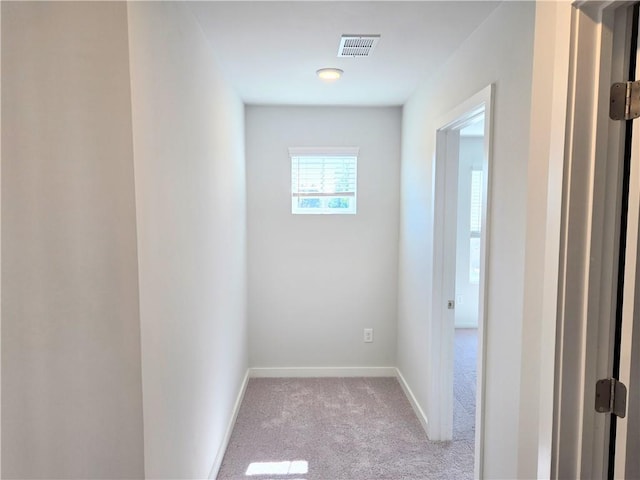 corridor with carpet, visible vents, and baseboards