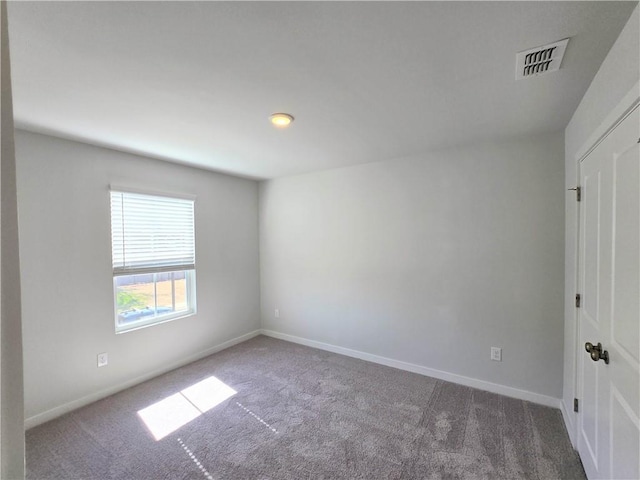 spare room with carpet floors, baseboards, and visible vents