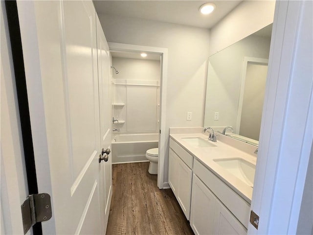 full bathroom featuring toilet, double vanity, a sink, and wood finished floors