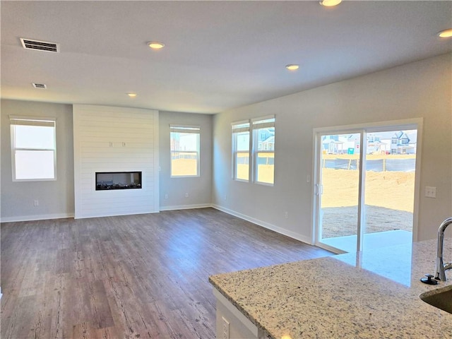 unfurnished living room with dark wood finished floors, a fireplace, recessed lighting, visible vents, and baseboards