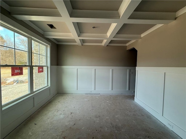 unfurnished room with beam ceiling, a wainscoted wall, coffered ceiling, and a decorative wall