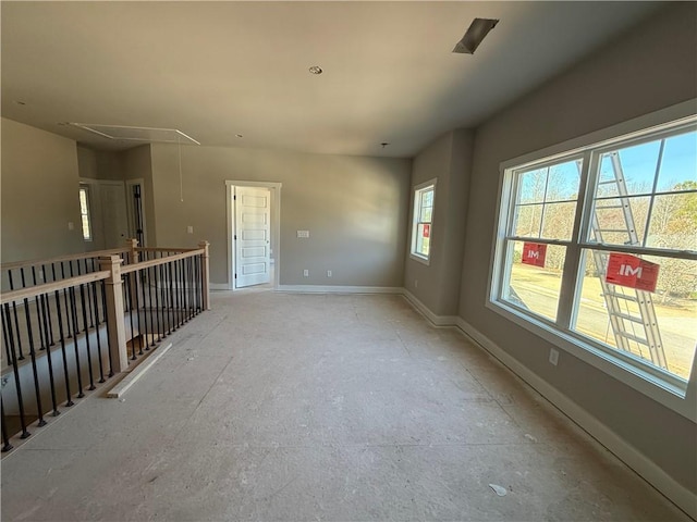 empty room featuring attic access and baseboards